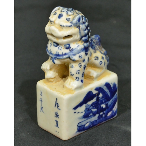 72 - An Oriental blue and white table seal in the form of dog of fo seated upon plinth with landscape dec... 