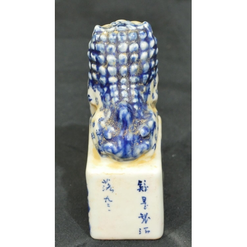 72 - An Oriental blue and white table seal in the form of dog of fo seated upon plinth with landscape dec... 