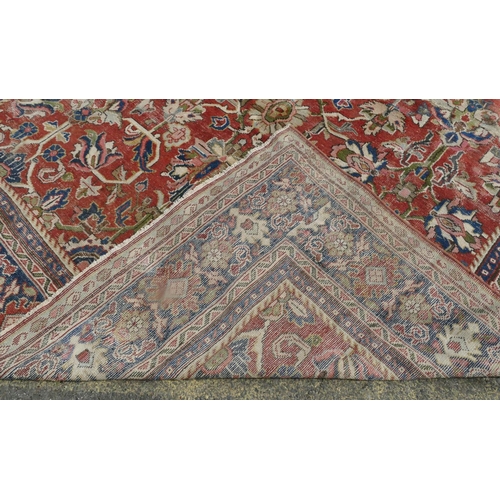 755 - A Persian carpet of red ground with allover decoration (worn), 355cm x 275cm.