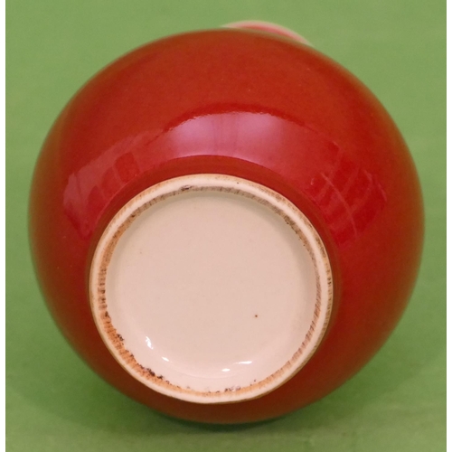 69 - An Oriental small round bulbous thin necked trumpet shaped vase on red ground, 15cm high.