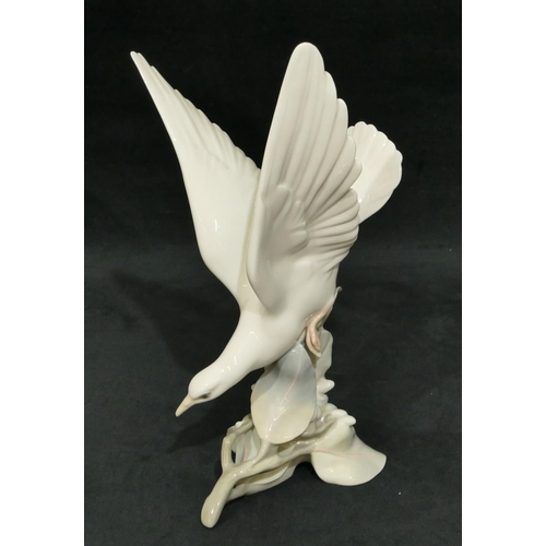 116 - A Lladro figure of a bird perched on a branch, 29cm high.