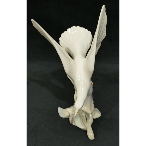 116 - A Lladro figure of a bird perched on a branch, 29cm high.