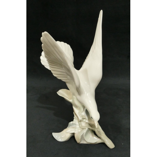 116 - A Lladro figure of a bird perched on a branch, 29cm high.