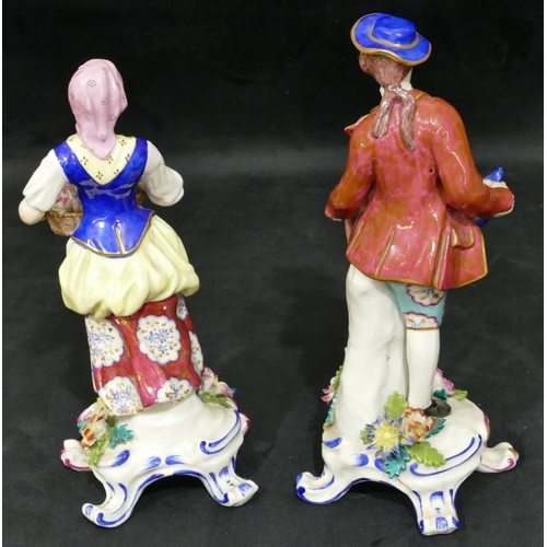 18 - A pair of Continental china figures of gentleman and lady holding encrusted flowers and fruit with s... 