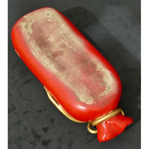 38 - An Oriental red china pillow in the form of a bag with gilt dragon decoration, 32cm long.