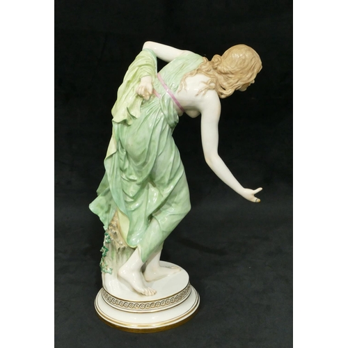 91 - A Meissen large figure of a lady stooping on round base (finger on right hand a/f), 35cm high.