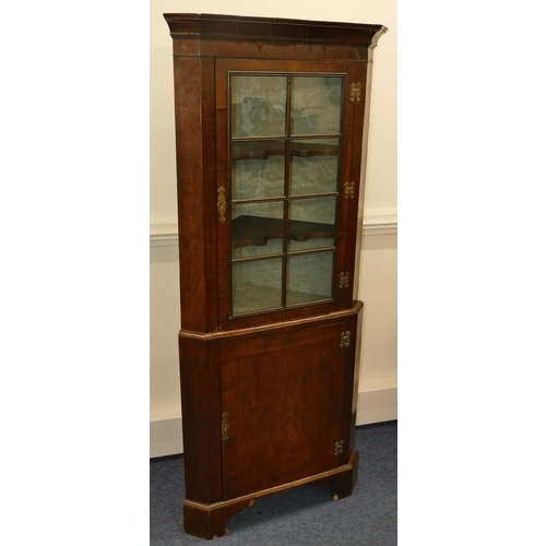 639 - A George III walnut freestanding corner cupboard with glass panel door enclosing shaped shelves, fur... 