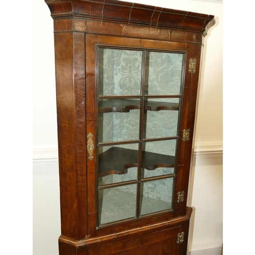 639 - A George III walnut freestanding corner cupboard with glass panel door enclosing shaped shelves, fur... 