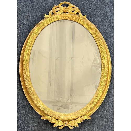 1175 - A 19th Century oval gilt hanging wall mirror having raised ribbon motif 82cm high  57cm wide