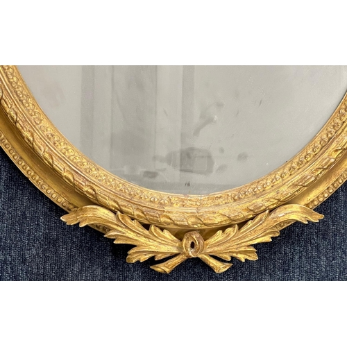 1175 - A 19th Century oval gilt hanging wall mirror having raised ribbon motif 82cm high  57cm wide