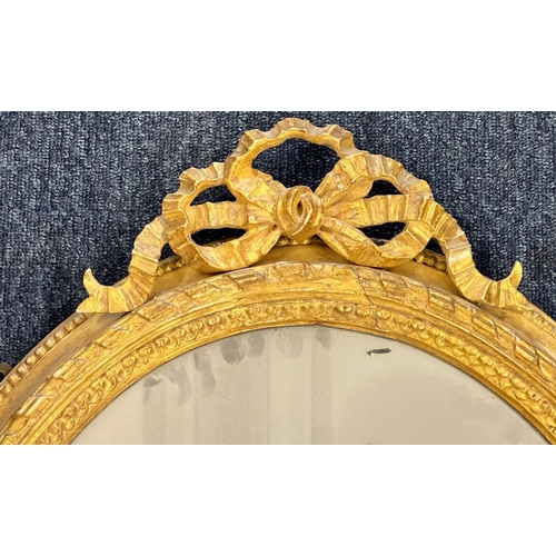 1175 - A 19th Century oval gilt hanging wall mirror having raised ribbon motif 82cm high  57cm wide