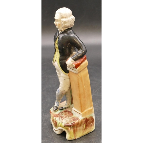 14 - An early Staffordshire figure of a standing gentleman holding a book on a pedestal with black jacket... 