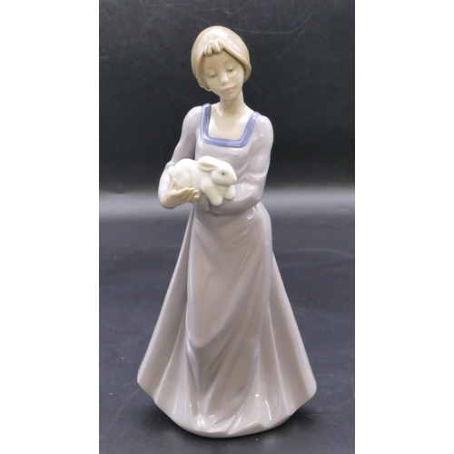 179 - A Nao figure of a young standing lady holding a rabbit, 25cm high.