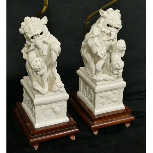 186 - A pair of Oriental Blanc de Chine figures of Dogs of Fo on plinths, 28cm high, both mounted on woode... 