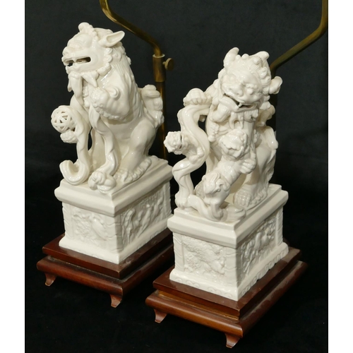 186 - A pair of Oriental Blanc de Chine figures of Dogs of Fo on plinths, 28cm high, both mounted on woode... 