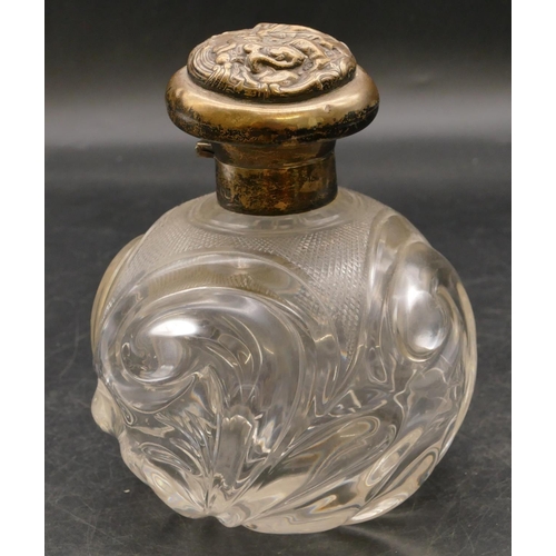 248 - A heavy cut glass round bulbous shaped scent bottle with London silver neck and hinged lid with embo... 