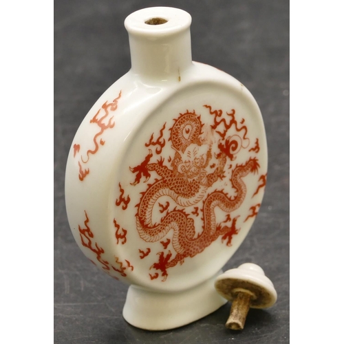 27 - An Oriental china moon flask shaped snuff bottle with stopper on white ground with red dragon decora... 