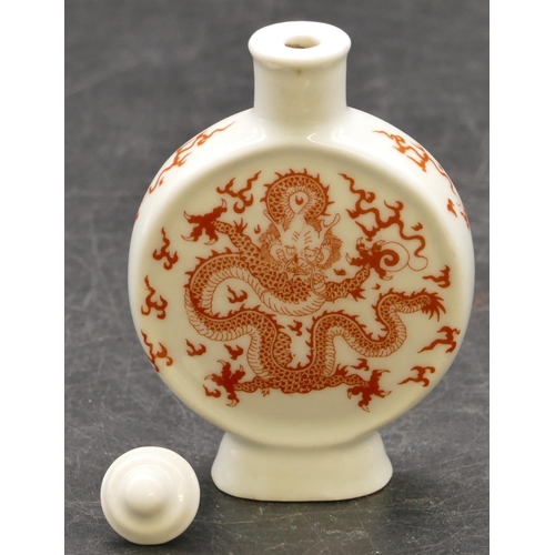 27 - An Oriental china moon flask shaped snuff bottle with stopper on white ground with red dragon decora... 