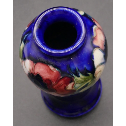 32 - A Moorcroft small round bulbous thin necked vase on blue ground with multi-coloured floral and leaf ... 