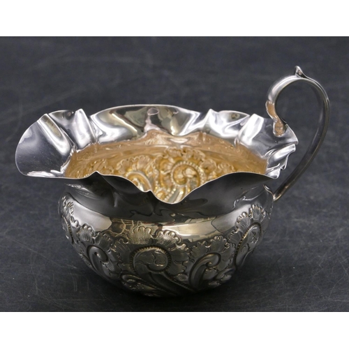 356 - A Sheffield silver round bulbous shaped cream jug with crinkled rim, embossed scroll and leaf decora... 