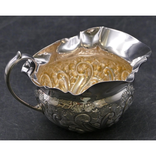 356 - A Sheffield silver round bulbous shaped cream jug with crinkled rim, embossed scroll and leaf decora... 