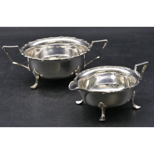 365 - A Sheffield silver round 2-handled scallop shaped sugar bowl and matching cream jug on splayed feet,... 