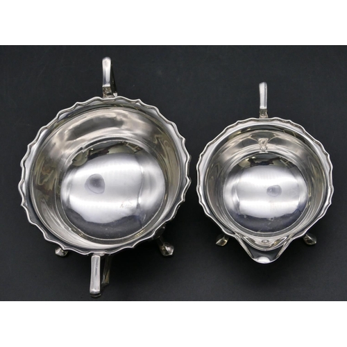 365 - A Sheffield silver round 2-handled scallop shaped sugar bowl and matching cream jug on splayed feet,... 