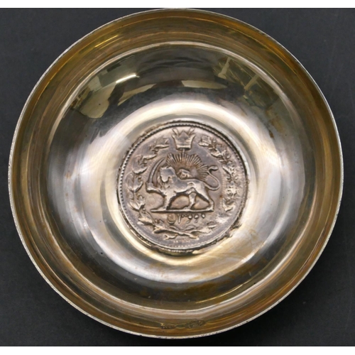 381 - A Continental silver coloured metal small round dish inset with Arabic coin with chased decoration, ... 