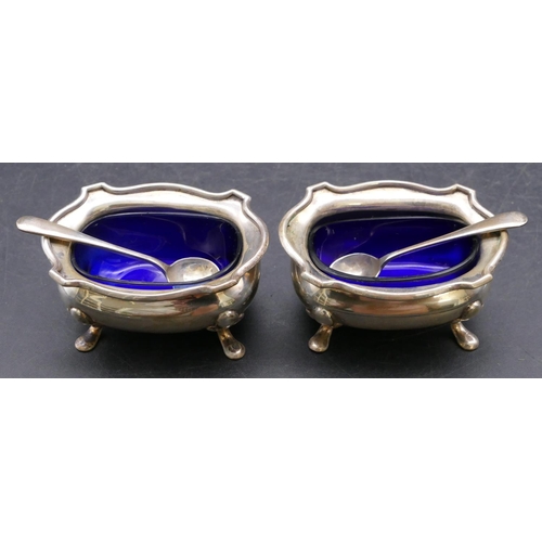 384 - A pair of Birmingham silver rectangular bulbous shaped salts with crinkled rims, blue glass liners o... 