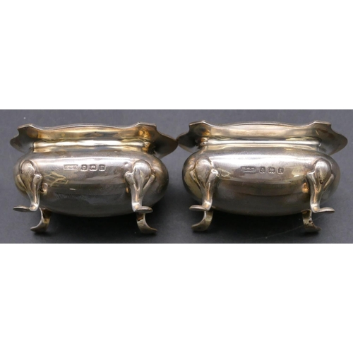 384 - A pair of Birmingham silver rectangular bulbous shaped salts with crinkled rims, blue glass liners o... 