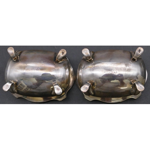 384 - A pair of Birmingham silver rectangular bulbous shaped salts with crinkled rims, blue glass liners o... 