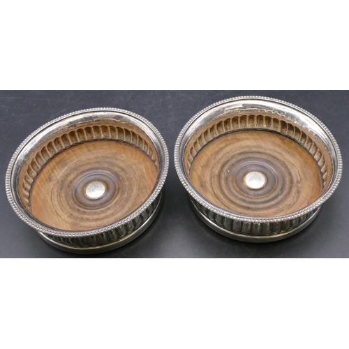 407 - A pair of early Victorian silver round bulbous shaped wine coasters with wooden centres, half emboss... 