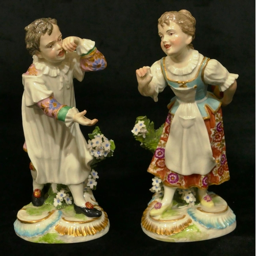 63 - A pair of Chelsea Derby porcelain figures of young gentleman and lady playing catch (both have branc... 