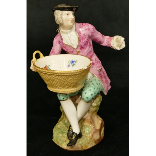 65 - A Meissen porcelain figure of a seated gentleman holding an oval basket (1 hand and thumb restored, ... 