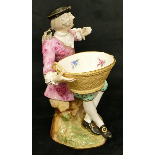 65 - A Meissen porcelain figure of a seated gentleman holding an oval basket (1 hand and thumb restored, ... 