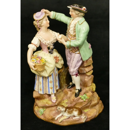 69 - A Meissen porcelain group of standing gentleman and lady holding a basket of encrusted flowers, dog ... 