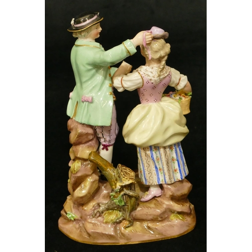 69 - A Meissen porcelain group of standing gentleman and lady holding a basket of encrusted flowers, dog ... 