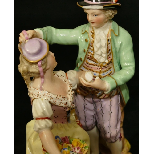 69 - A Meissen porcelain group of standing gentleman and lady holding a basket of encrusted flowers, dog ... 