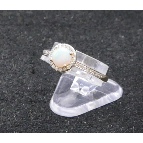 748 - A 9ct gold ladies' circular ring set with centre opal, surrounded by diamond chips with further diam... 