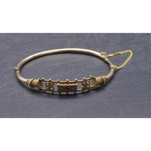 756 - A 9ct gold bangle set with centre red stone and half pearls (clasp in need of restoration), 7.5 gram... 