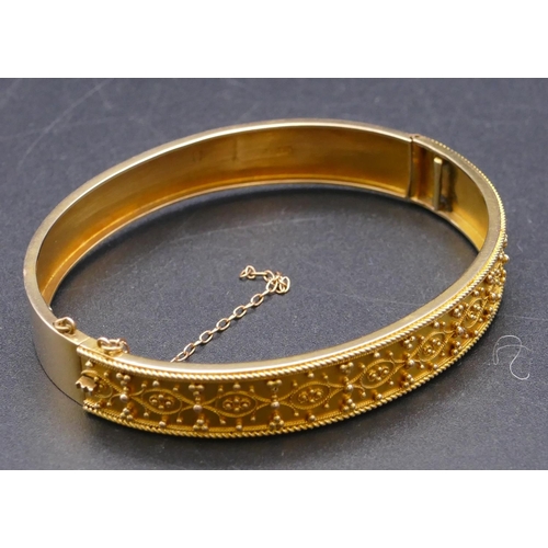 808 - A 15ct gold hinged bangle with raised decoration, 13.1 grams