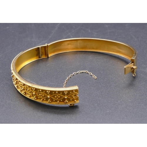 808 - A 15ct gold hinged bangle with raised decoration, 13.1 grams