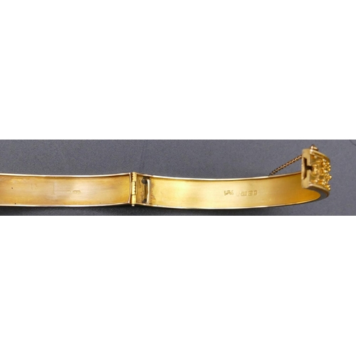 808 - A 15ct gold hinged bangle with raised decoration, 13.1 grams