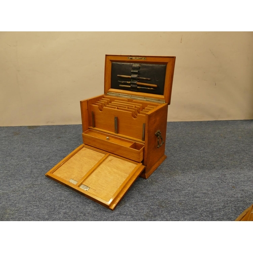 829 - An oak stationery box with hinged top and drop front enclosing stationery rack, pen drawer etc, bras... 