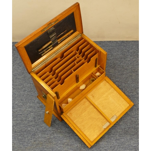 829 - An oak stationery box with hinged top and drop front enclosing stationery rack, pen drawer etc, bras... 