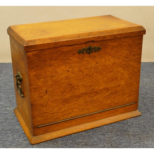 829 - An oak stationery box with hinged top and drop front enclosing stationery rack, pen drawer etc, bras... 