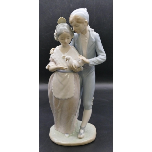 180 - A Nao group of a young gentleman and lady holding a dove, 32.5cm high.