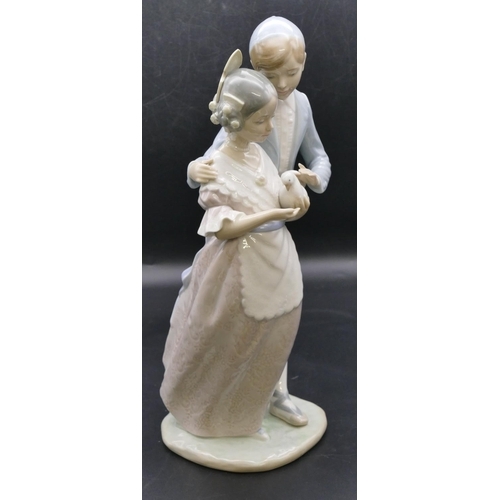 180 - A Nao group of a young gentleman and lady holding a dove, 32.5cm high.