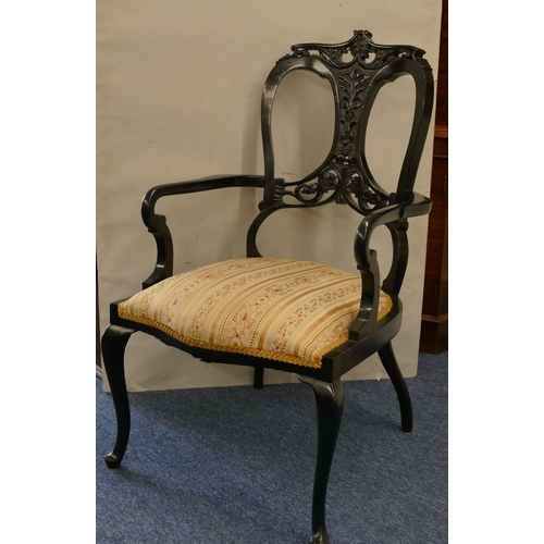 1166 - An ebonised armchair with pierced and raised carved floral, leaf and pierced decoration, floral over... 