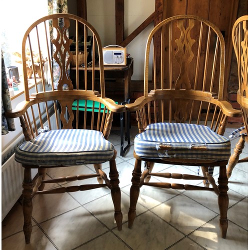 6140 - A pair of pine comb back Windsor armchairs, 119cm high, 65cm wide, with blue and white cushions (wor... 